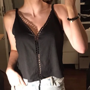 Svart topp - Svart top med en tända längs bröstkorgen som man kan se igen. Jätte skön att ha på sommaren väldigt luftig men fortfarande bekväm