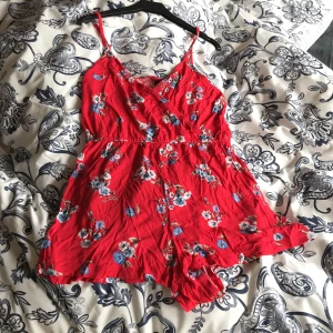  Röd jumpsuiten med blommor på,  - I storlek 34