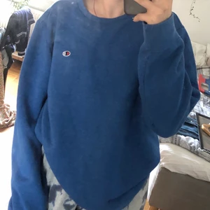 Blå Champion sweatshirt  - Mysig blå sweatshirt med en liten ”champion detalj”. Tröjan är liten i storlek men ändå snygg och bekväm. denna tröja är perfekt om man vill ha en mer ”relaxed outfit” och passar helt perfekt till ett par jeans eller kostymbyxor. 