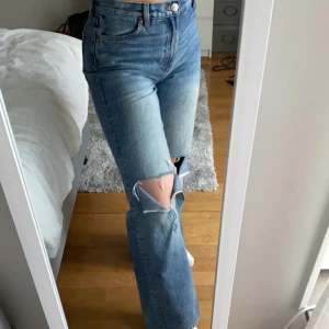 Blåa jeans - Säljer dessa snygga jeans från Monki. Egen gjorda hål på båda knäna. Vida ben och hög midja. Kontakta mig för fler bilder om du är intresserad.