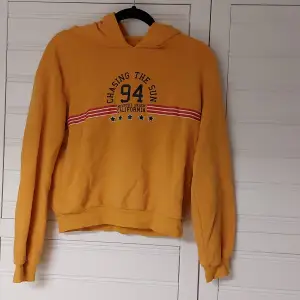 Lite kortare hoodie i senapsgul färg med tryck 