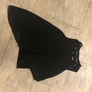 Svart blus - Svart blus med vita pärlor vid halskragen och är lite längre på vänster sida (på bilden, höger sida i verkligen) fint skick använd ca 2 gånger