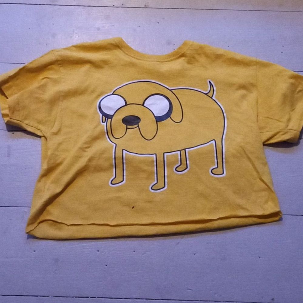 T-shirt från Fruit of the loom med Jake från Äventyrsdags som jag klippt till en magtröja. Knappt använd. Står inuti att det är storlek 140 men passar bra på en liten XS. Lite sprickor i trycket (se bild) men inga andra skador/fläckar. BETALNINGSMETOD: SWISH (PÄLSDJUR I HEMMET). T-shirts.