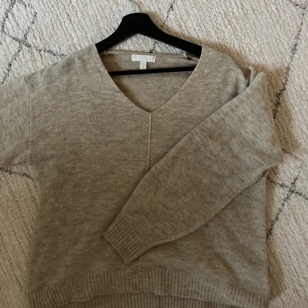 V-ringad stickad tröja i beige/grå färg. Bjuder på frakt vid snabb affär. Stickat.