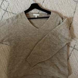 V-ringad stickad tröja i beige/grå färg. Bjuder på frakt vid snabb affär