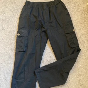 Cargobyxor - Svarta raka cargo byxor i jättebra skick. De har fickor på sidorna och på rumpan. Storlek M och passar unisex. Säljer då de aldrig kommer till användning👌🏻🤛🏻