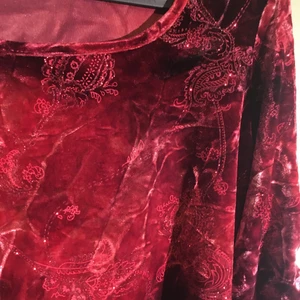 röd festlig tröga ifrån kappahl - en skiftande röd festlig tröja av samet med glittriga detaljer. man kan typ dra upp armarna med ett snöre med armarna elr bara lämna som den e.