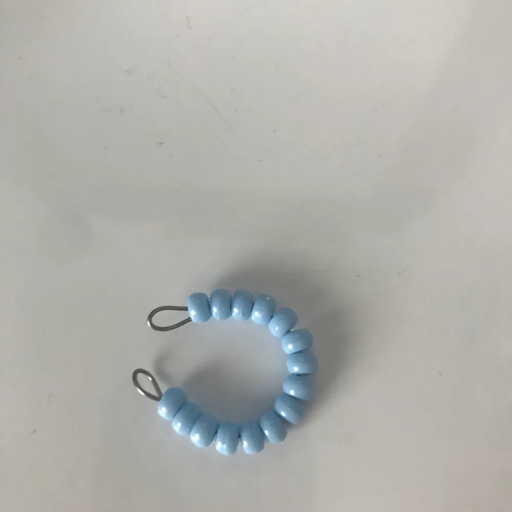 Ringen är gjord av ståltråd och har ljusblåa pärlor🦕.      Ringen är öppen och då justerbar så den passar alla fingrar!. Övrigt.