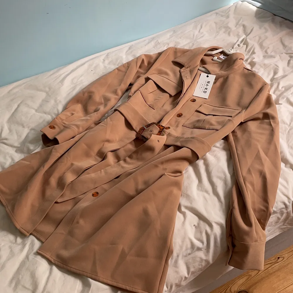 beige/brun nakd kappa med bälte, storlek 38. aldrig använd och prislapp finns kvar original pris 549kr. Jackor.