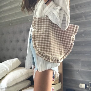 Tygväska med volang  - En tygväska med volang sydd av ett beige rutigt second hand tyg. Väskan är ca 27 cm djup utan fickor. En perfekt strandväska eller en enkel axelväska!!