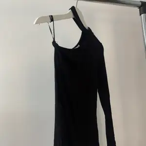 Något figursydd svart tunna tröja med en arm och en ”chocker” 