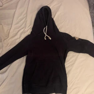 Marinblå hoodie - ❤️En hoodie i strl S från New Yorkers herravdelning i en djupblå/ marinblå färg med läderimitations detaljer på dragskosnörena och en på överarmen med märkets logga. Den är ganska liten i storleken och är inte lång eller oversized. Den går typ till höfterna. Köps för 30kr✨ och köparen står för frakt🥰