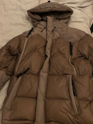 Brunbeige pufferjacka från Mountain Works - Säljer en brunbeige pufferjacka från Mountain Works i storlek L. Jackan har huva, dragkedja, flera fickor och smarta detaljer som tumhål i muddarna. Använd fåtal gånger, nyskick! Pris går att diskutera vid snabb affär💗