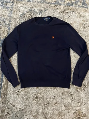 Mörkblå tröja från Polo Ralph Lauren - Säljer en mörkblå tröja från Polo Ralph Lauren i slim fit. Tröjan är gjord av mjuk pima bomull och har en klassisk rund halsringning samt det ikoniska broderade logot på bröstet. Perfekt till både jeans och chinos.