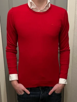 Röd stickad tröja från J.Lindeberg - Säljer en röd stickad tröja från J.Lindeberg med diskret logga på bröstet. Tröjan har rund halsringning och långa ärmar. Funkar året runt för en clean och stilren look🍾 Vid den 3 bilden så ser man en av få defekter på tröjan, därefter en till på magen. man måste stå nära för att se! Tröjan har ett fint material som du kan slänga på och få en confident boost direkt! Tröjan är i storlek S men mindre i storleken som omfattar Xs, Tveka inte att fråga om något känns oklart, det är bara att köra på✨