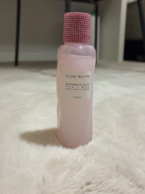 Glow Recipe Watermelon Glow Toner - Glow Recipe Watermelon Glow PHA + BHA Pore-Tight Toner i en ljusrosa plastflaska med en glittrig rosa kork. Tonern har en fräsch vattenmelon-doft och är perfekt för att ge huden lyster och minimera porer.