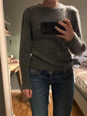 Mörkgrå stickad tröja - Mysig mörkgrå stickad tröja med rund hals och långa ärmar. Perfekt för kyliga dagar och enkel att matcha med jeans eller kjol. Tröjan har en klassisk passform och känns riktigt skön mot huden.