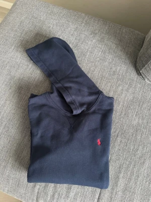 Polo Ralph Lauren marinblå hoodie - Säljer en Polo Ralph Lauren marinblå hoodie från Kids Brand Store i storlek 170, motsvarar XS/S. Köptes förra året och kommer inte till användning så mycket.