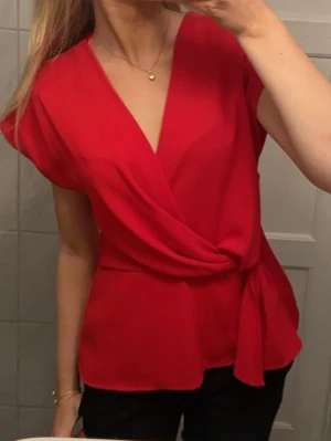 Röd omlottopp med knyt - Snygg röd omlottopp från Zara med v-ringning och knyt i midjan. Storlek xs