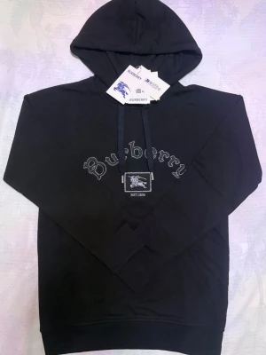 Burberry Tröja - Hej! Säljer en snygg och stilren svart hoodie från Burberry. Den svarta färgen gör den enkel att matcha med allt och funkar lika bra till vardags som till en mer clean outfit. Perfekt för dig som vill ha både komfort och lyx i ett och samma plagg 😊❄️