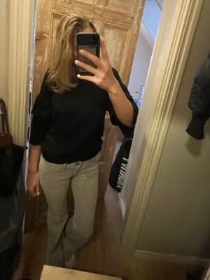 Svart tröja med volangärmar - Svart stickad tröja med trekvartsärmar och snygga volangdetaljer på ärmarna. Enkel men ändå trendig!