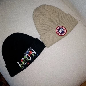 Båda för 300  - Två ribbstickade mössor säljes! Ena är svart från Dsquared2 med färgglad ICON-logga framtill, den andra är beige från Canada Goose med klassisk rund patch. Båda har uppvikt kant och är perfekta för kalla dagar. Hela och rena äkta så klart och mycket fint material på dom sitter väldigt fint och bekvämt 300 för båda perfekt till vintern