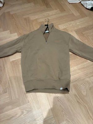 Beige half zip från Les Deux XS  - Säljer en beige half zip-tröja från Les Deux i storlek XS. Tröjan har hög krage, dragkedja framtill och broderad logga på bröstet. Tillverkad i mjuk bomull och passar perfekt för en chill och stilren look. Den är storlek XS enligt lappen men den sitter väldigt stort, passar män 175-180 ungefär. Köpt för runt 1500 kronor för ett år sedan 