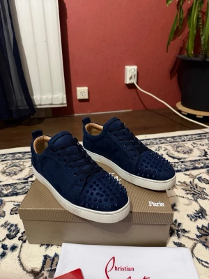 Marinblå sneakers från Christian Louboutin - Söker byten på dessa loubs mot ett par rena gråa med spikar eller hel mörkblåa utan spikar kan oxå sälja dem.
