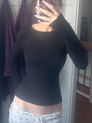 Svart långärmad topp - Säljer en enkel och stilren svart långärmad topp i stretchigt material. Modellen är tight och har rund halsringning. Perfekt att matcha med jeans eller kjol för en clean look.