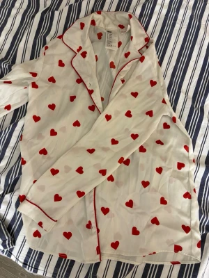 🤍 Vit silkespyjamas med röda hjärtan – H&M 🤍 - Säljer en jättefin pyjamas från H&M i silkesliknande material. Vit botten med röda hjärtan – supergullig och trendig 💕 Setet består av både skjorta och byxor.  • Storlek: 158/164 • Skick: Väldigt bra skick, sparsamt använd • Material: Silkesliknande (mjukt och glansigt) • Passform: Bekväm och luftig  Perfekt som pyjamas, myskläder eller till en cool outfit om man stylar den rätt ✨ Hör av dig vid frågor eller om du vill ha fler bilder!