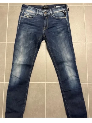 Replay skinny jeans blå, storlek 26/30 - Snygga blå skinny jeans från Replay i modellen LUZ. Jeansen har klassisk femficksdesign, ljusa slitningar och kontrastsömmar. Midjan är normal och materialet är mjukt jeans med stretch. 