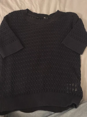stickad topp - Säljer en marinblåa stickad topp från lager157 i storlek XS. Tröjan har ett genombrutet mönster, ribbade muddar och korta ärmar. Perfekt för lager på lager och ger en cool vibe till din outfit.