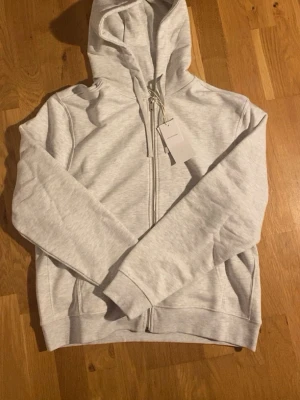 Zara Hoodie - Grå hoodie med dragkedja från Zara. Säljer eftersom att jag köpte för stor storlek. Tröjan är helt oanvänd och lappen finns kvar. Skicka ifall du har frågor eller funderingar😊. !!Postar inom 24h!!
