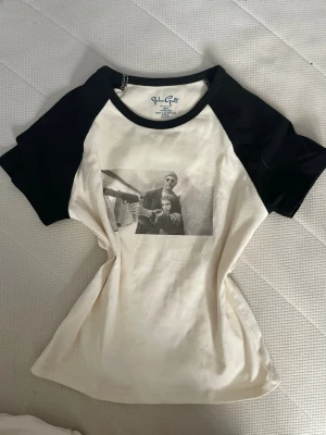 Brandy Melville svartvit t-shirt med Leon filmen motiv - Säljer en svartvit t-shirt från brandy med kontrastfärgade svarta ärmar och ett grafiskt tryck (Léon filmen) framtill. Aldrig använd! Klassisk baseballmodell med rund hals och korta ärmar. Perfekt för dig som gillar streetstyle och vill sticka ut lite extra.