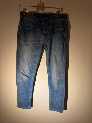 Ljusblåa dondup jeans - Snygga och stilrena Dondup jeans – modell George (Skinny Fit) i klassisk blå tvätt. Ett premiumplagg från Italien med bra passform och fina detaljer.  ✔️ Märke: Dondup✔️ Modell: George✔️ Passform: Skinny fit✔️ Storlek: 34✔️ Färg: Blå denim✔️ Skick: Bra begagnat skick✔️   Jeansen har normal midja, smal benform och funkar perfekt både till vardag och mer uppklädda outfits. Tidlös tvätt som aldrig går ur stil.  Nypris för Dondup jeans ligger högt – perfekt chans.