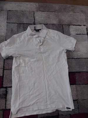 Vit pikétröja från Didriksons XS - Klassisk vit pikétröja från Didriksons i storlek XS. Tröjan har korta ärmar, krage och knappar framtill. Tillverkad i mjuk bomull som känns skön mot huden. Enkel och stilren design som passar till det mesta.