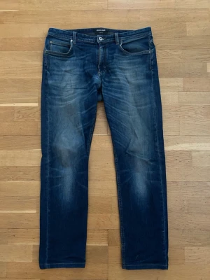 Blå jeans från Roberto cavelli - Säljer ett par klassiska blå jeans från Roberto cavelli med snygg tvätt och raka ben. Jeansen har fem fickor, normal passform och subtila slitningar för en avslappnad look. Perfekta till sneakers eller boots och funkar året runt. Nytt pris 8000