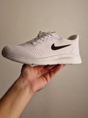 Vita Nike sneakers med svart swoosh - Du hittar inte sånna här priser. Välj ett par stilrena vita JÄTTE JÄTTE !AA! ORGINELLA Nike sneakers med svart swoosh på sidan. Ovandelen är i ventilerande mesh. Yttersulan är mönstrad för extra grepp och skon är lätta. Perfekt för träning eller vardagligt bruk. Kvalite och möjlighet att inte bekymra dig över bördan att smusta ner vita sneakera för priset du betalar. Sorlek passar 42-44!