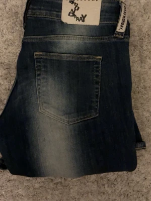 Blå bootcut jeans från Cheap Monday - Säljer ett par blå bootcut jeans från Cheap Monday med tydliga slitningar och ljusa partier framtill och baktill. Klassisk femficksmodell med normal passform och låg midja. Jeansen har en snygg tvättad look och breda ben, perfekt till sneakers eller boots. Säljer då de tyvärr är för stora för mig💞