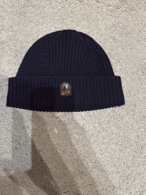 Mörkblå mössa från Parajumpers - Snygg mörkblå mössa från Parajumpers helt ny från Johnells. Fick med den när jag köpte en jacka därifrån och jag passar inte i den. Nypris 749 och säljer den för 500 från början. Pris kan diskuteras. MVH Viktor 