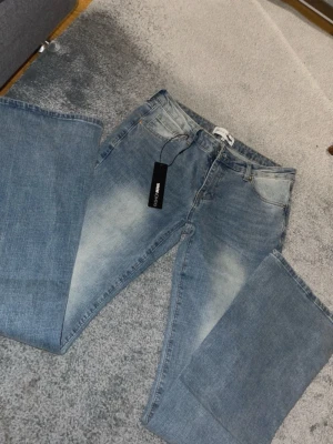 Blå lowrised jeans från fashion nova  - Snygga ljusblå jeans från fashion nova. Jeansen har en lätt tvättad look  och är tillverkade i mjukt bomullsmaterial. Perfekta för dig som gillar retrovibbar och vill ha ett par jeans med lite extra attityd.
