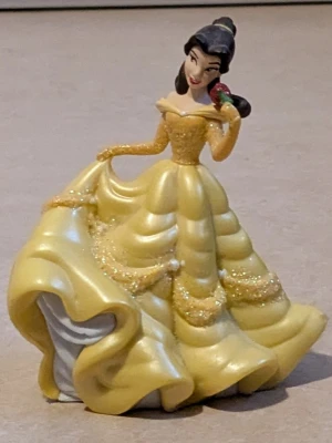  Belle från skönheten och Odjuret , Disney figur  - Disney figur, Belle från Skönheten och Odjuret. Belle har på sig en klänning. Klänningen har en lång, böljande kjol med glittriga detaljer och offshoulder-ärmar. Perfekt för dig som älskar sagolika och pampiga Disney figurer. Mycket bra skick har endast använts som dekoration 