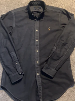 Ralph Laurent skjorta  - En felfri Ralph Laurent skjorta i Classic fit perfekt för nyår och passar som en smäck på alla som bär storlek M eftersom den är lite stor i storleken!   Den är i en blå/grå aktig färg och väldigt unik! Hör av dig vid intresse! 