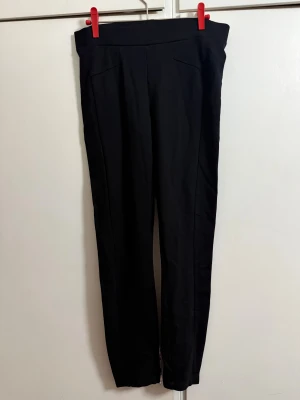 Svarta kostymbyxor från Esprit S - Svarta kostymbyxor från Esprit i storlek S. Byxorna har en rak och smal siluett med hög midja och diskreta sömmar framtill. Materialet känns mjukt och har en lätt stretch för extra komfort. Perfekta för en clean och stilren look.