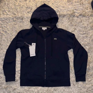 Mörkblå lacoste zipper - Mörkblå Lacoste zipper, storlek S, i nytt skick (aldrig använt) och bästa material, skriv om ni har frågor