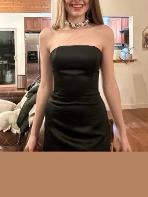 Figurnära svart klänning - Pris kan diskuteras! Snygg svart bandeau klänning. Den formar kroppen såå fint och är glansig liknar siden material. Använd en gång och den är i fortfarande i 10/10 skick inga defekter. Den har dragkedja i ryggen. Perfekt till nyår☺️