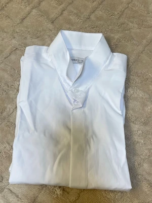 Vit slim fit skjorta från Enrico Viti - Snygg vit skjorta från Enrico Viti i slim fit-modell. Skjortan har klassisk krage, långa ärmar och svarta manschettknappar som ger en cool kontrast. Tillverkad i bomull för en skön känsla och stilren look. Perfekt för dig som gillar enkel och fräsch stil.