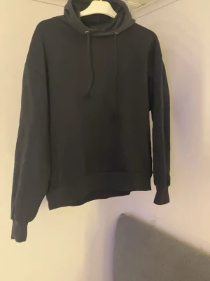 Svart hoodie från lager 157 - Svart hoodie från lager 157. En bra tröja att ha till vardags till ex ett par jeans eller mjukisbyxor. Ganska liten luva med snörning framtill