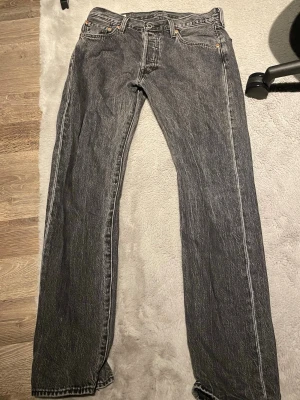 Levi's 501 svarta jeans W30 L32 - Säljer ett par klassiska Levi's 501 jeans i svart tvättad denim. De har rak passform, fem fickor och knappgylf. Ikonisk läderpatch bak i midjan och röda Levi's-taggen på bakfickan. Perfekta till en avslappnad streetwear-look.