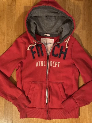 Abercombrie & Fitch vintage hoodie zip - En snygg röd vintage hoodie från A&F med dragkedja😁Inga defekter förutom slitningar i ärmslut som ger en extra vintagekänsla🤩! Storlek L, passar folk över 180cm. Är 176cm på bilden. Tveka inte på att skicka prisförslag och frågor!😁